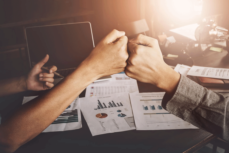 A close up of coworkers fist bumping in front of a desk full of work documents. This could represent achieving more career and personal fulfillment in Ontario, CA. Learn more about online therapy in Ontario & learn more about finding self fulfillment in Ontario today.