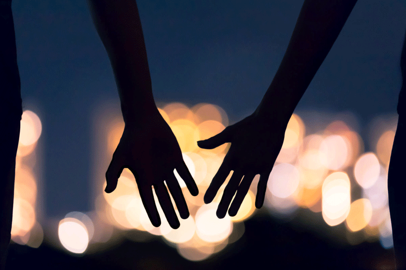 A close-up of a couple reaching for each other’s hands against the background of city lights at night. This could represent the closer bonds cultivated after working with an Ontario therapist. Learn more about creating a fulfilling relationship in Ontario, CA. Search for feeling fulfilled in a relationship Toronto, CA. 