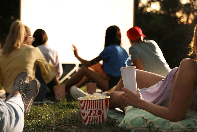 A crowd of people rests in the grass with blankets in front of an outdoor cinema screen on a sunny evening. This could represent the bonds cultivated with family and friends. Learn more about how to cultivate self fulfillment in Toronto, CA today. Search for “lack of fulfillment toronto, ca” to learn more today.